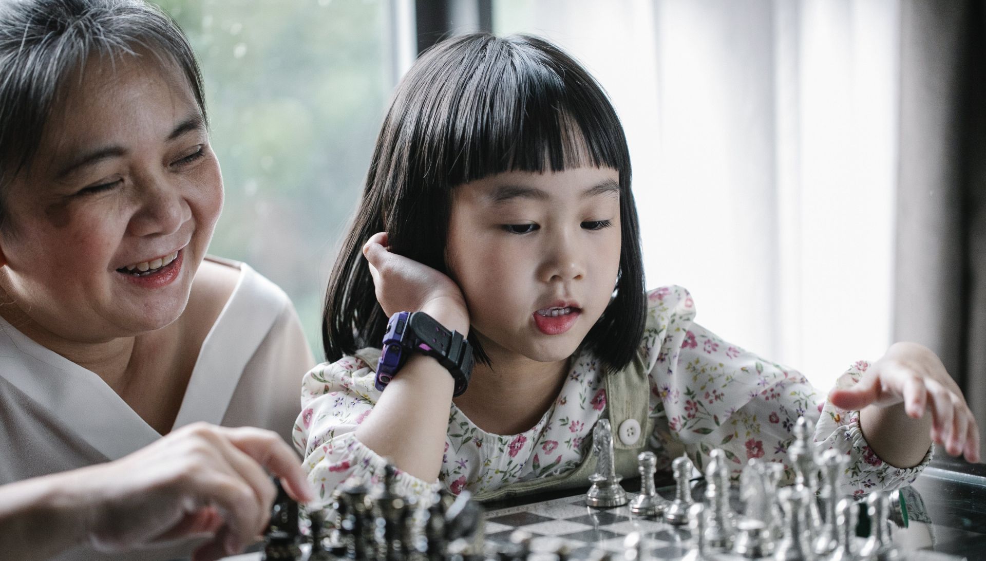 Child playing chess with grandmother